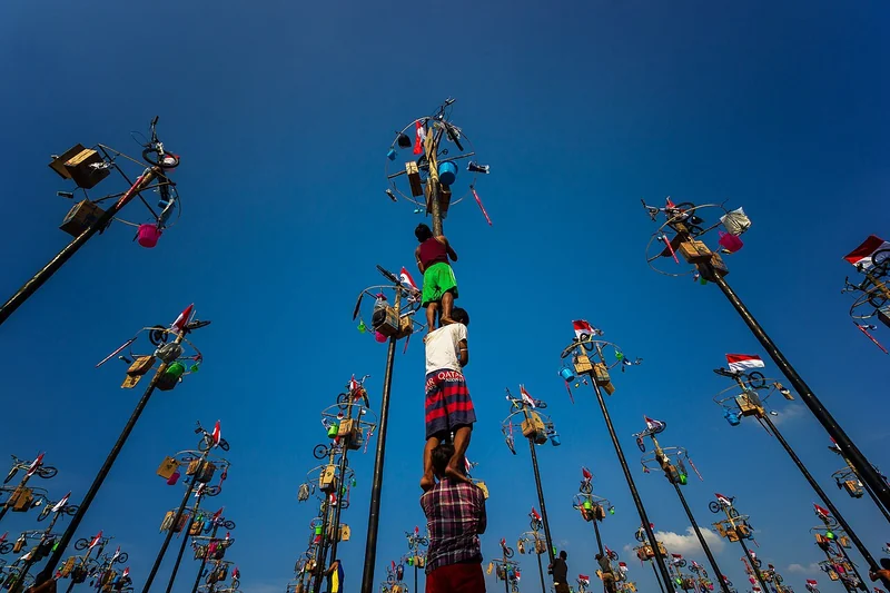 Foto lucu lomba panjat pinang 17 Agustus dengan peserta bersusun di pundak dan puluhan batang berhadiah